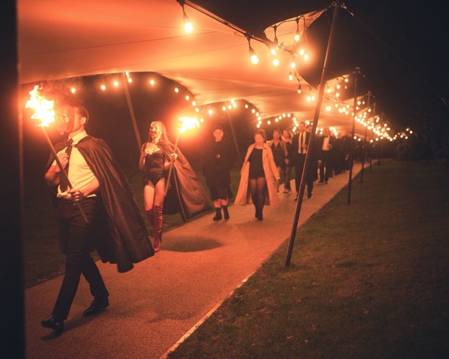 Grupp musta riietatud inimesi järgneb kahele leeki kandvale inimesele