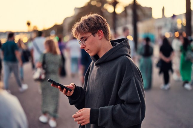 Teismeline poiss kasutab telefoni Nice'i Promenade des Anglais'l, Alpes-Maritimes, Prantsusmaa.