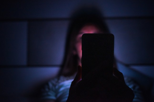 Tundmatu naine öösel voodis telefoni vahtimas