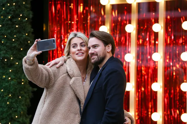 Paari, keda on nähtud piduliku aknaekraaniga selfiet tegemas