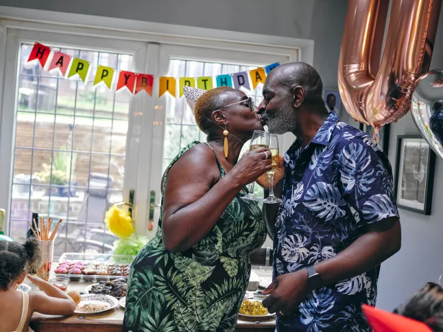 Täiskasvanud paar sünnipäevapeol suudlemas