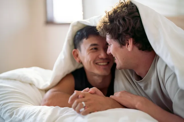 Romantiline noor geipaar, kes veedab koos voodis mõnusalt aega.