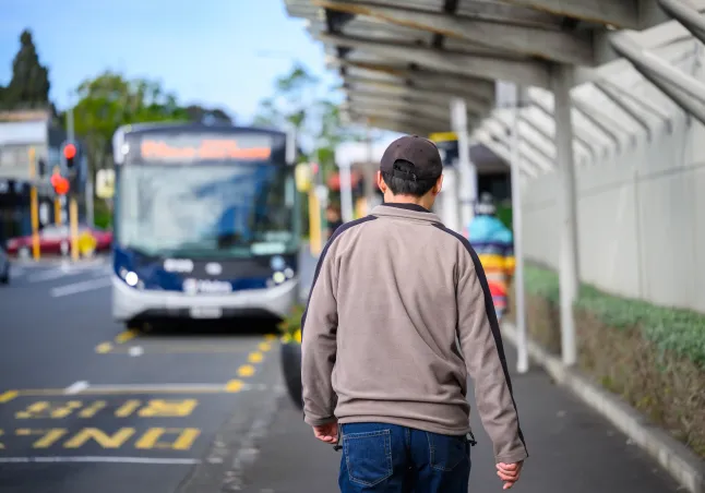 Mees kõnnib linnatänaval bussipeatuses bussi poole. Auckland.