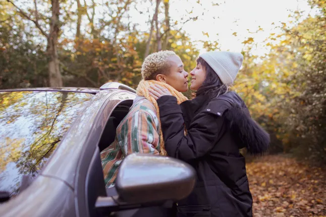 Suurbritannia, London, Richmond, Lesbi paar suudleb sügismetsas auto juures