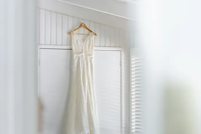 Valgusküllases toas puidust riidepuul rippuv elegantne valge kleit