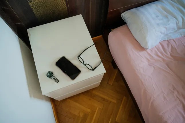 Telefon, prillid ja käekell öökapil.