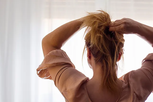 Naine selja tagant oma juukseid korjamas