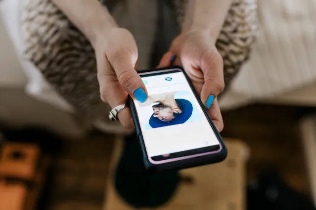 Naise käed hoiavad telefoni, millel kuvatakse kohtamisrakendus