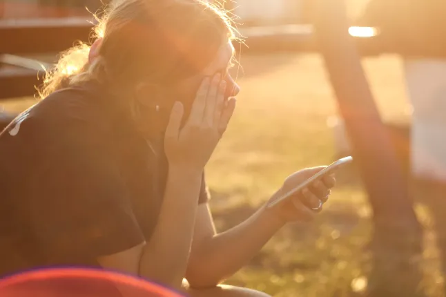 Küberkiusamine ja võrguahistamine: teismeline tüdruk, kes nutab, telefon käes, sümboliseerides Interneti ohtu ja emotsionaalset vägivalda