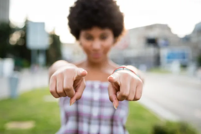 Lokkis juustega tüdruk osutab sulle tähelepanu. Hägune efekt.