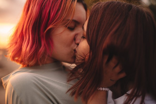 Lesbipaar suudleb suvel päikeseloojangul