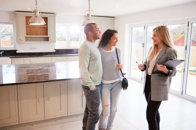 Naine kinnisvaramaakler, kes näitab paari, kes on huvitatud maja ostmisest; Shutterstocki ID 1470587294; ostu_tellimus: -; töökoht: -; klient: -; muu: -