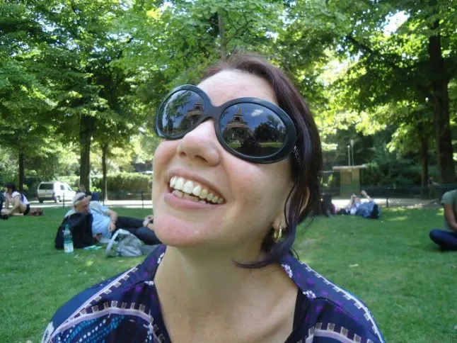 Georgia Lewis (ainult pea/õlgad) naeratab pargis, päikeseprillid ees