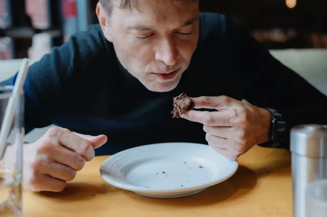 Lähivõte täiskasvanud mehest, kes lõpetab restoranis fudge brownie't